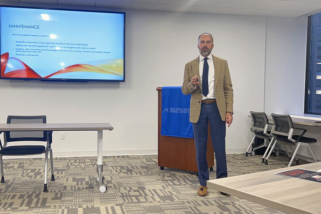 David Abayev lecturing at the New York County Dental Society, a maintenance slide on the screen