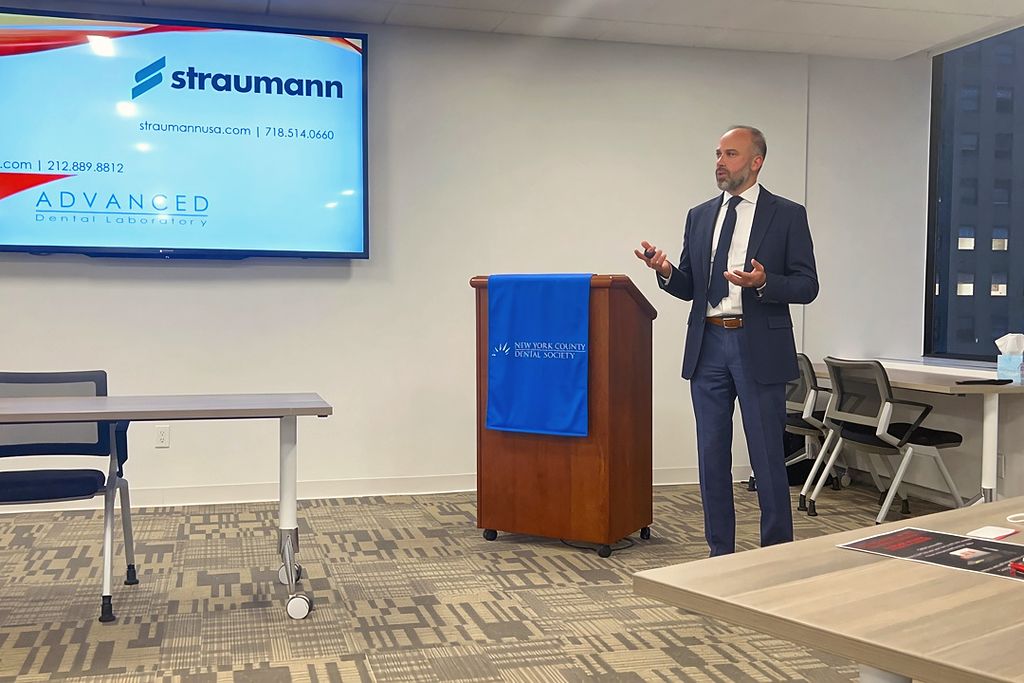 David Abayev presenting beside a Straumann and Advanced Dental Laboratory title slide at the New York County Dental Society